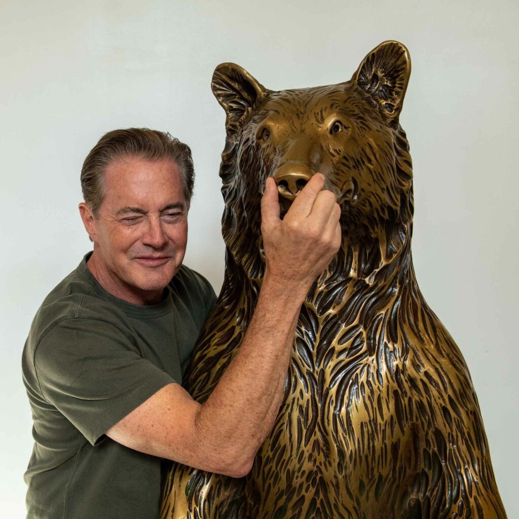 Kyle posing with bear statue- his hand is over the bear's mouth