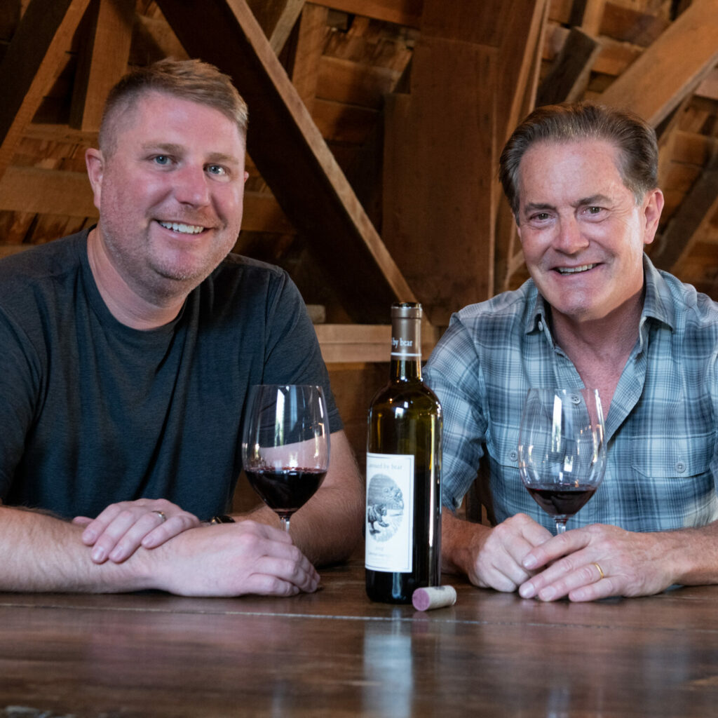 Dan and Kyle sitting at a table enjoying a glass of wine