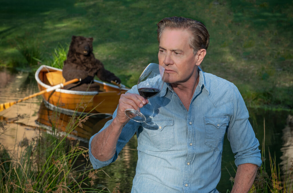 Kyle smelling wine while Bear rows boat in background