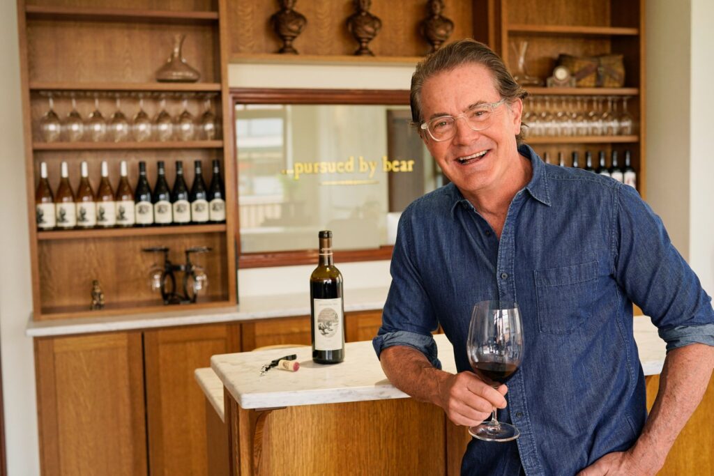 Kyle with arm on bar, with glass of red